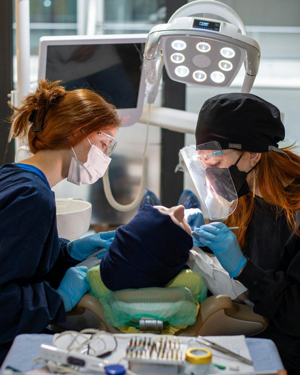 Dentista e auxiliar realizando procedimento em paciente